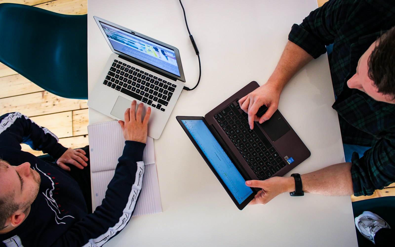 Two people working side by side on laptops, seen from above
