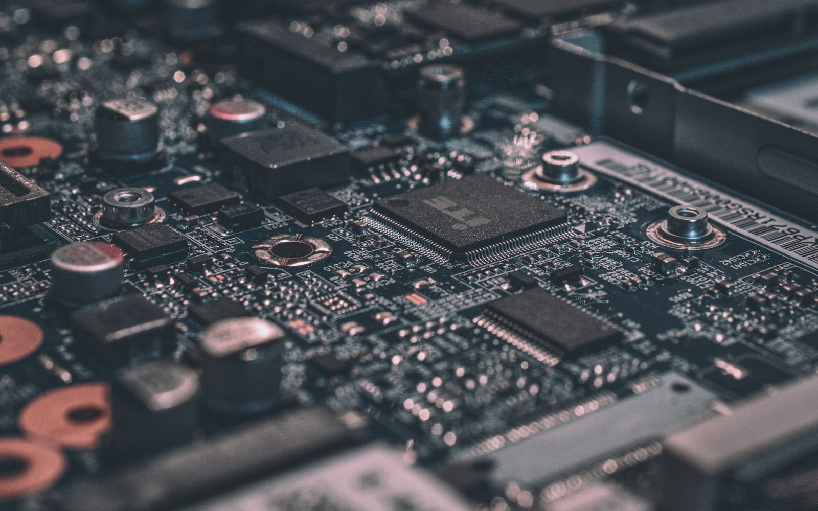 Macro photograph of a dark circuit board with chips and capacitors