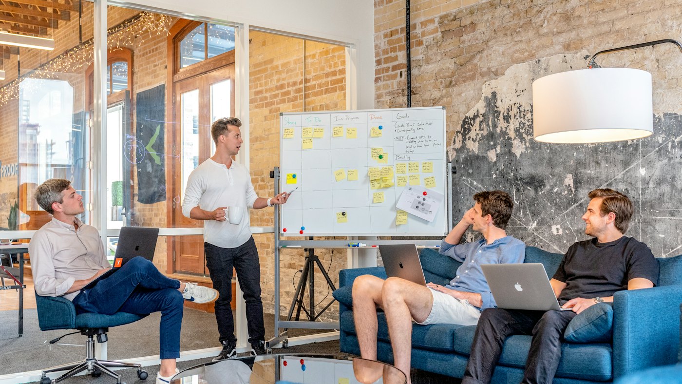Team gathered around a whiteboard of sticky notes planning work