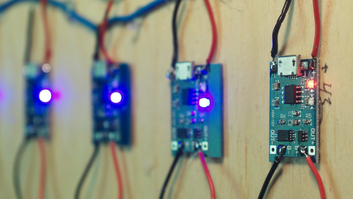 Four small microcontroller boards wired up with their status LEDs lit